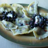 Pyszny przepis na pierogi z jagodami mrożonymi. Podane z bitą śmietaną i świeżymi jagodami.