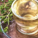 Aromatyczny napar z oregano, pełen dobroczynnych właściwości, w szklanej filiżance na rustykalnym tle.
