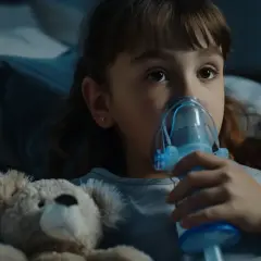 Dziewczynka z misiem robiąca inhalację nebulizatorem.
