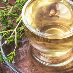 Aromatyczny napar z oregano, pełen dobroczynnych właściwości, w szklanej filiżance na rustykalnym tle.