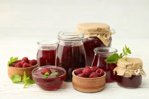 Słoiki z domowym dżemem malinowym i świeże maliny. Idealny sok z malin przepis na lato.