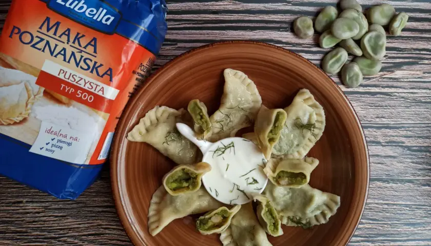 Pyszne pierogi z bobem, podane z kwaśną śmietaną i koperkiem, obok mąki Lubella.