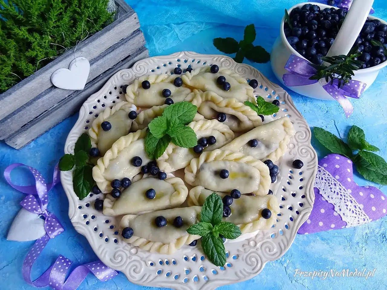 Pyszne pierogi z jagodami mrożonymi, ozdobione świeżą miętą i borówkami. Idealne na letni deser.